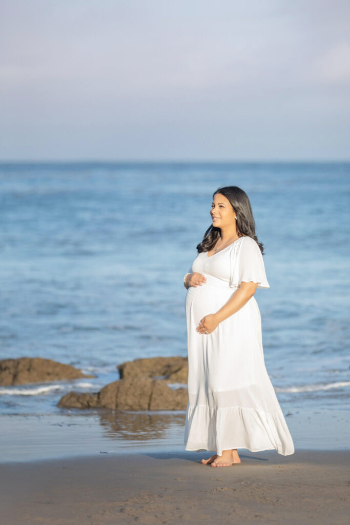 Maternity photoshoot at Malibu beach with mom to be holding her baby bump