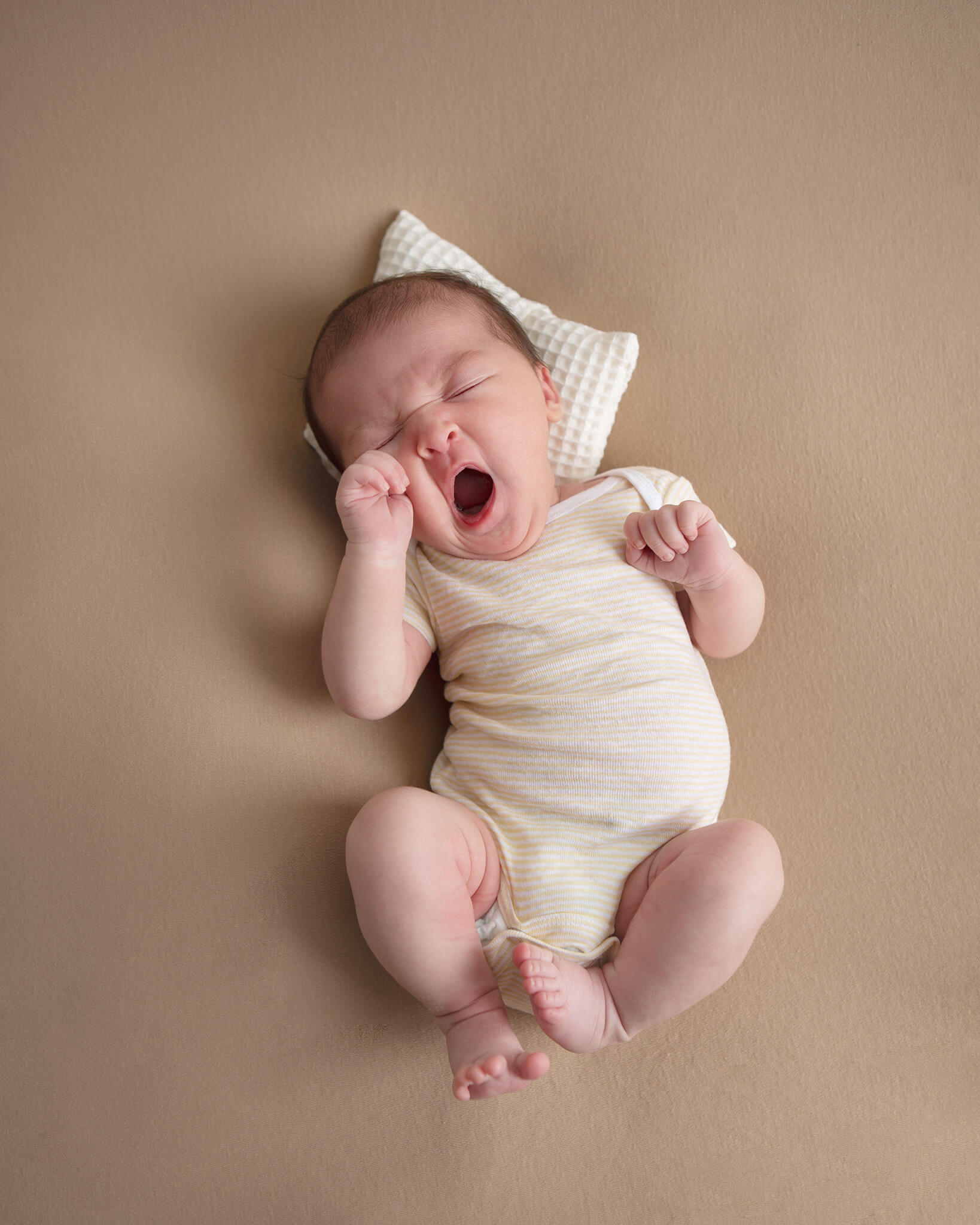 Newborn baby yawning laying on a little pillow at newborn photoshoot - Cedars Sina Maternity Ward