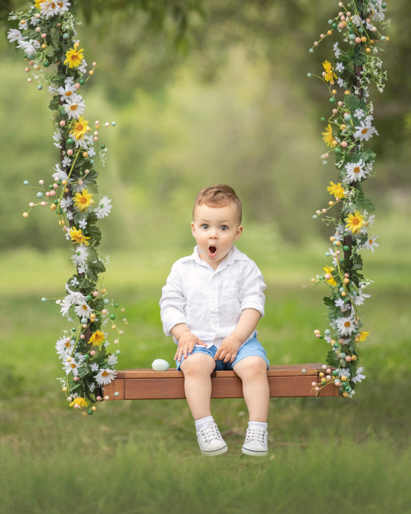Little boy sitting on a spring swing of flowers in Los Angeles - Little Blue Boutique Calabasas