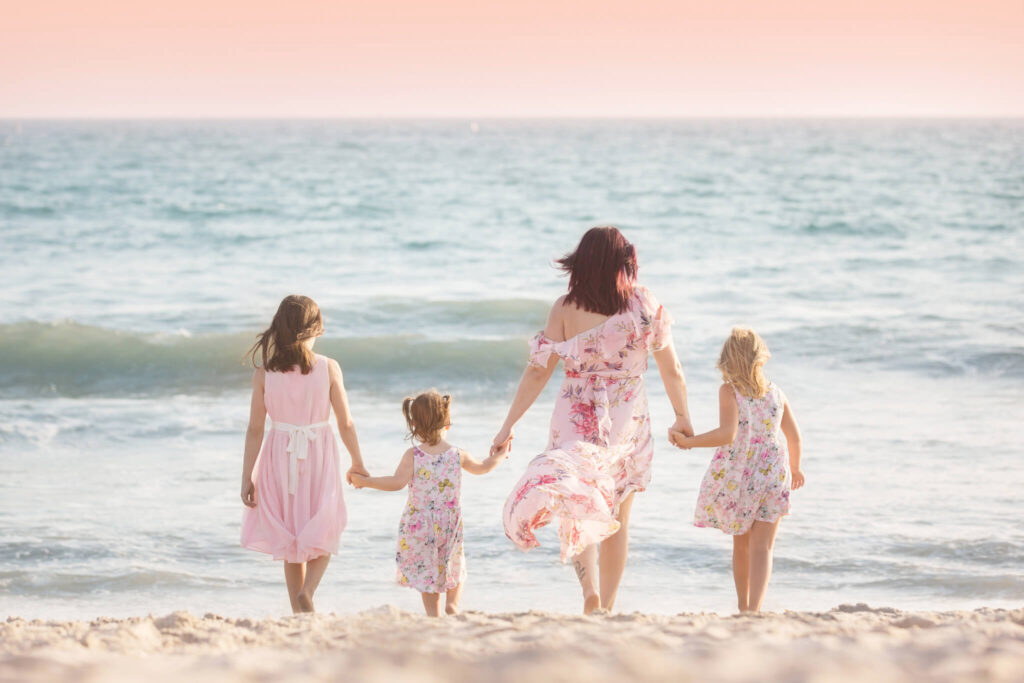 Family holding hands and walking towards the water by Elsie Rose Photography in Los Angeles - beach photoshoot outfit ideas