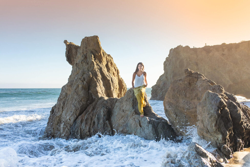high school senior photographed at El Matador beach while sitting on a rock