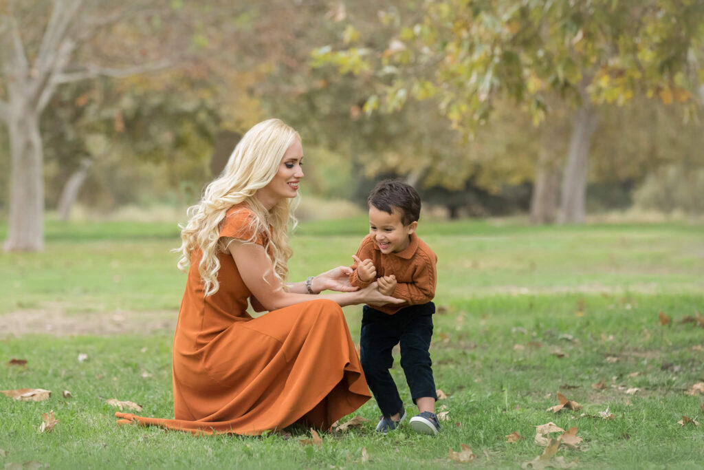 Mom laughing with her son at holiday mini session in los angeles. Wearing burnt orange dress and sweater