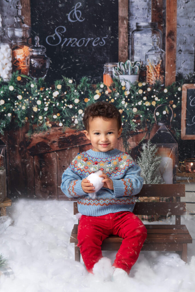 Little boy holding a snow ball wearing a blue sweater holiday mini sessions in los angeles