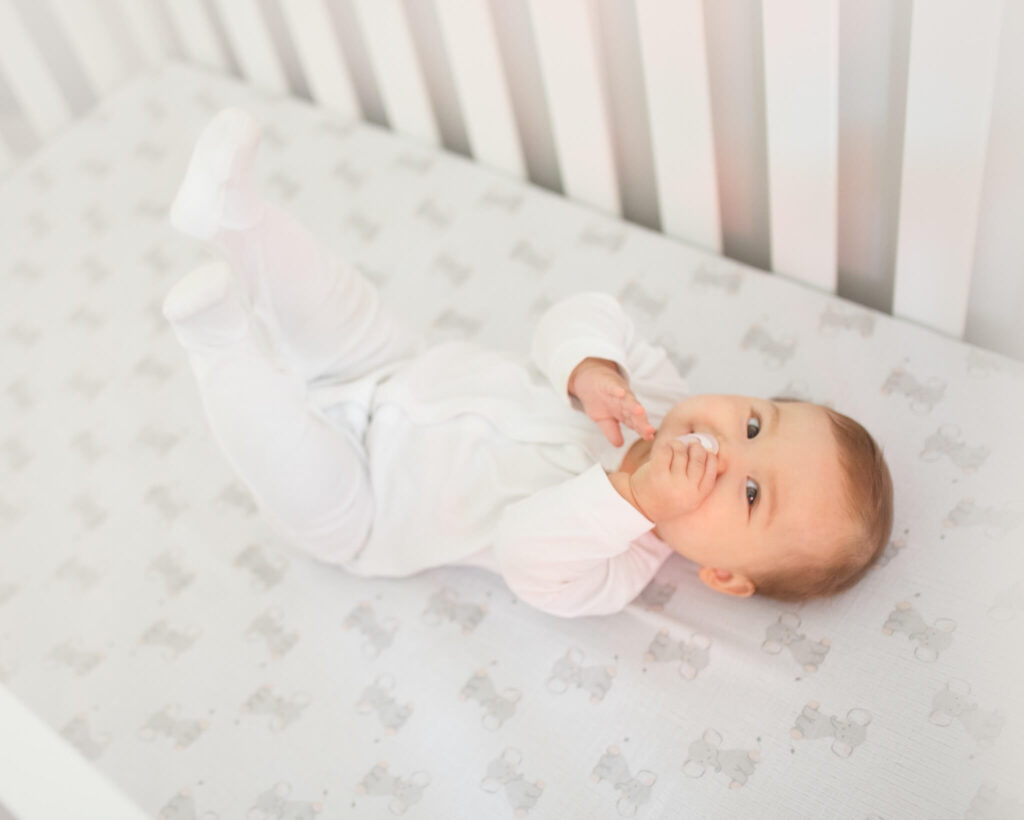 Baby laying in crib all in white - 3 highly regarded Nanny agencies in Los Angeles