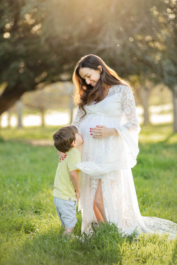 Pregnant mom with her little son kissing her baby bump in maternity photoshoot - Hatch Brentwood