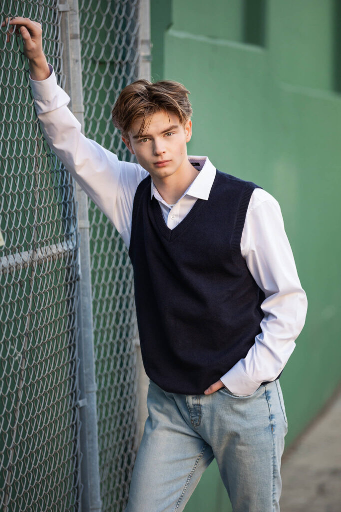 Teen boy photo session in Los Angeles wearing jeans and blue sweater and leaning on a railing