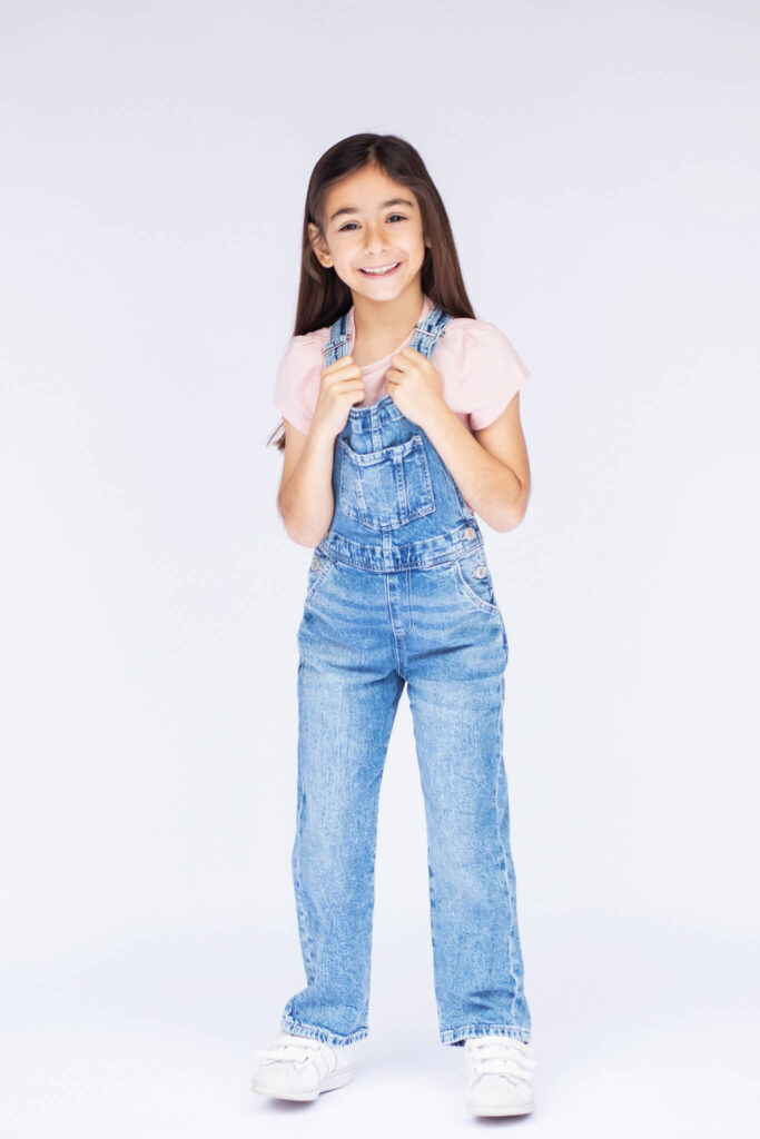 Little girl wearing dungarees on a white backdrop photographed in Woodland Hills