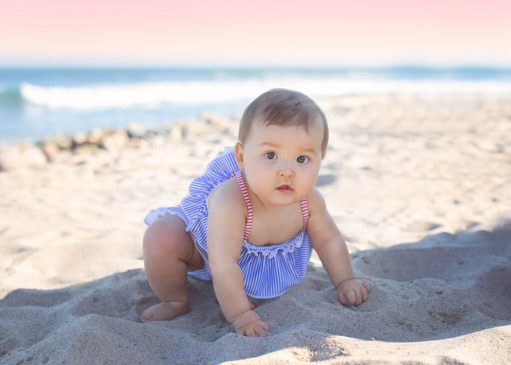 Baby girl in blue and white striped swimsuit at a Malibu beach