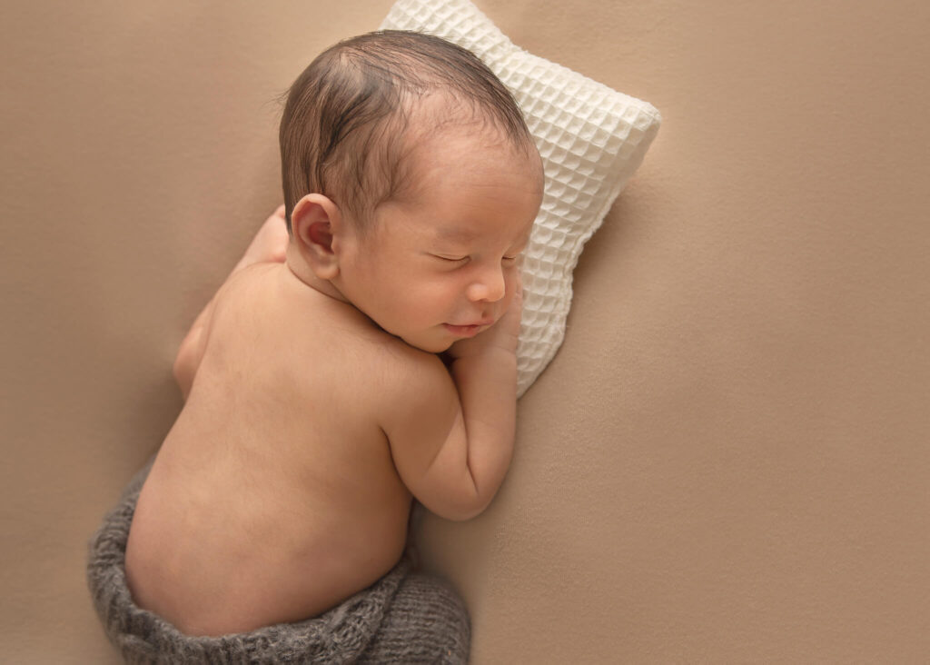 Newborn baby asleep on a tiny white pillow - Sherman Oaks Pediatricians