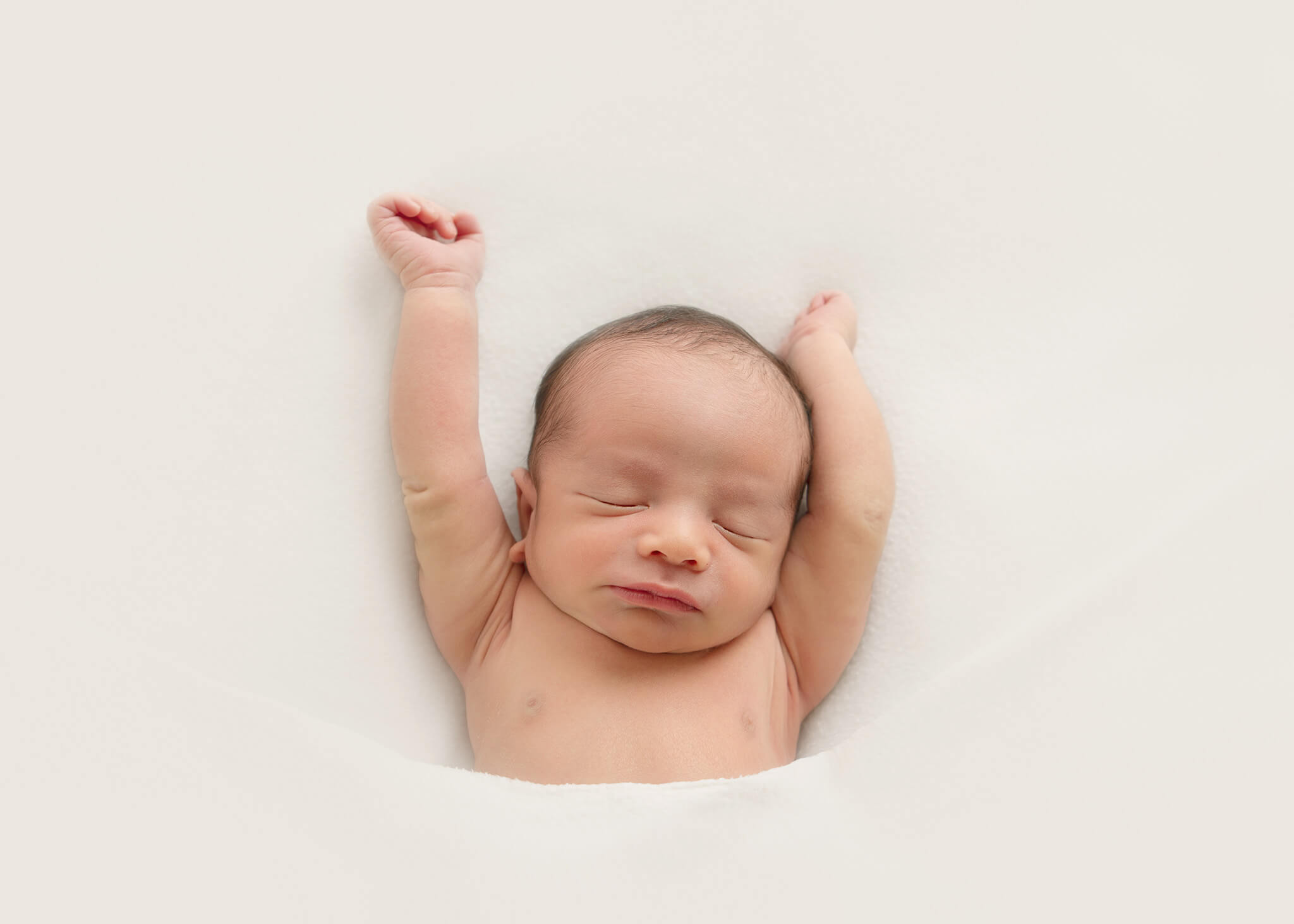 Baby boy on white blanket and stretching while waking up - Sherman Oaks Pediatricians