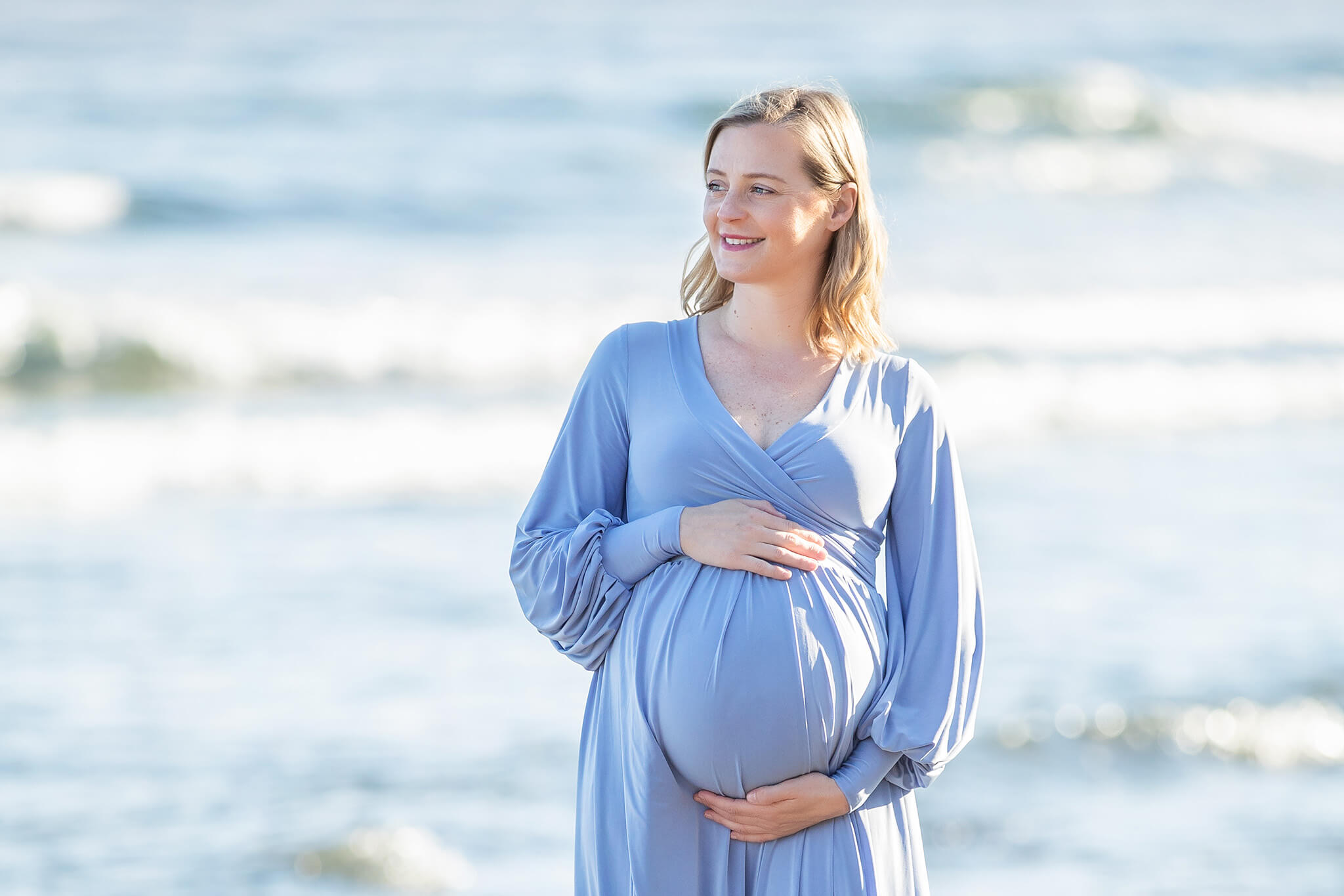 Mom to be wearing a blue dress at beach in Malibu - Birth Center Los Angeles