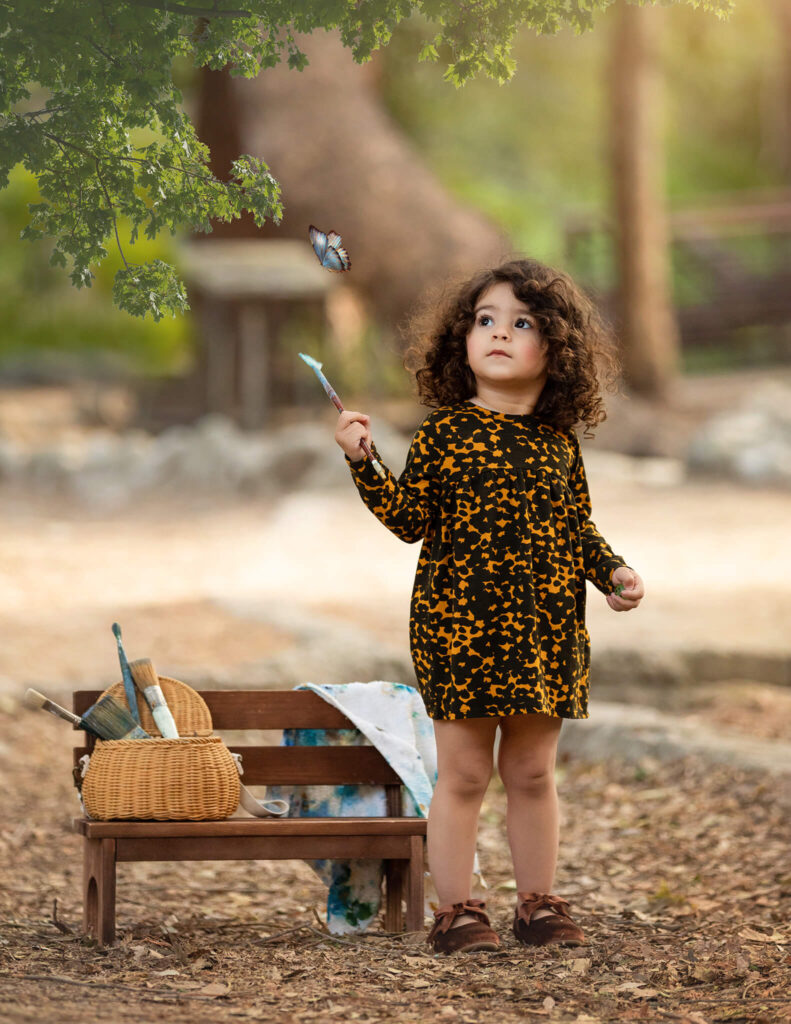 Little girl with a paint brush watching a butterfly in the park in a magical image by Elsie Rose Photography - Pre Schools in Studio City