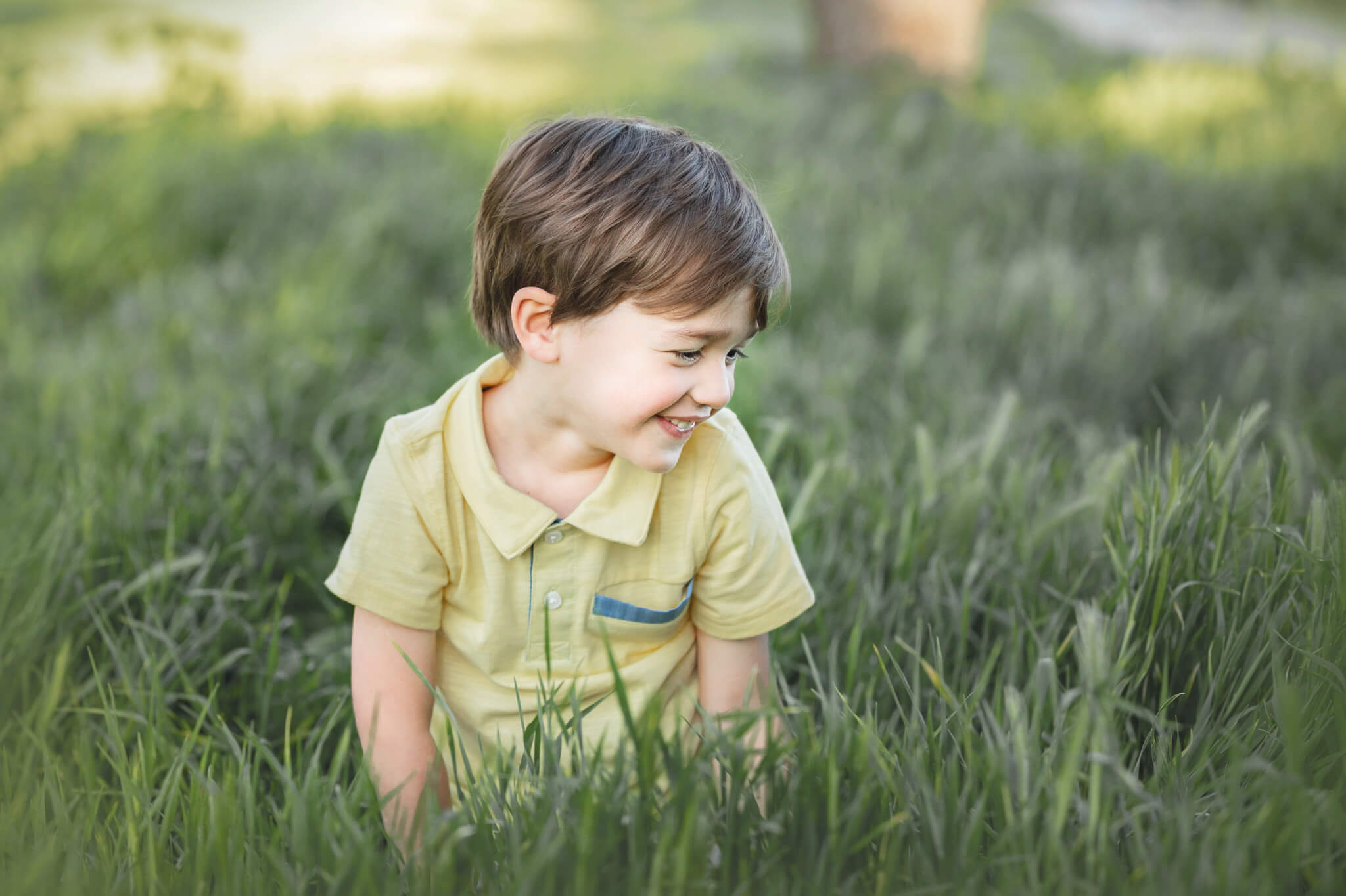 Little boy in the grass laughing, wearing a yellow shirt. - Pre Schools in Studio City