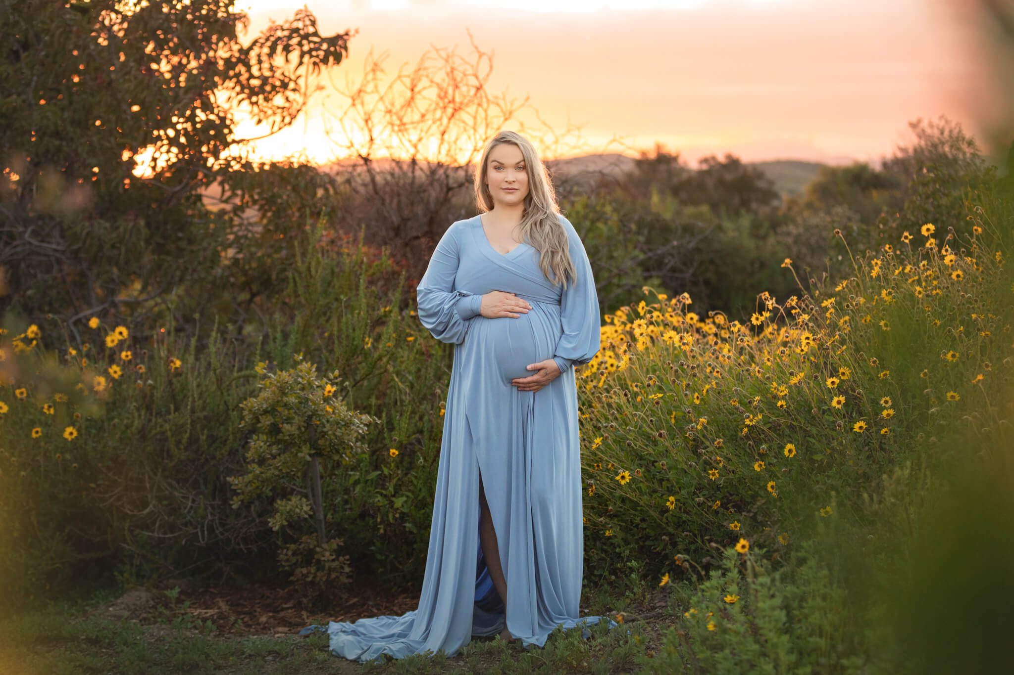 Maternity image of mom to be in a blue dress with LA sunset behind - los angeles doula