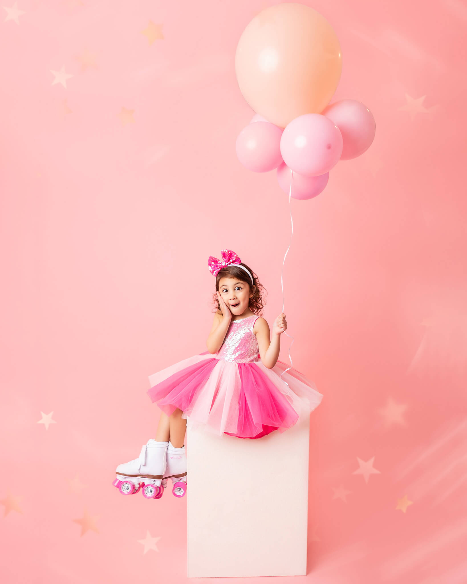 Little girl sitting on a box in a barbie dress with pink balloons for her birthday - Posh and Petite Playhouse