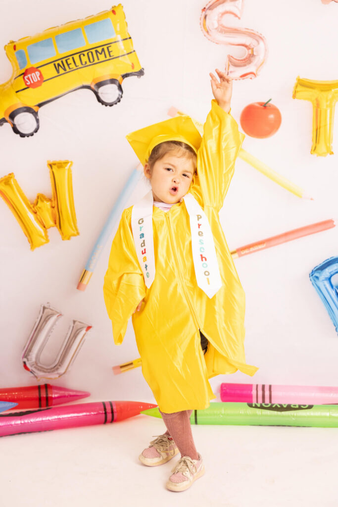 preschool girl graduating with arm punched in the air. Preschool and kindergarten graduation in LA