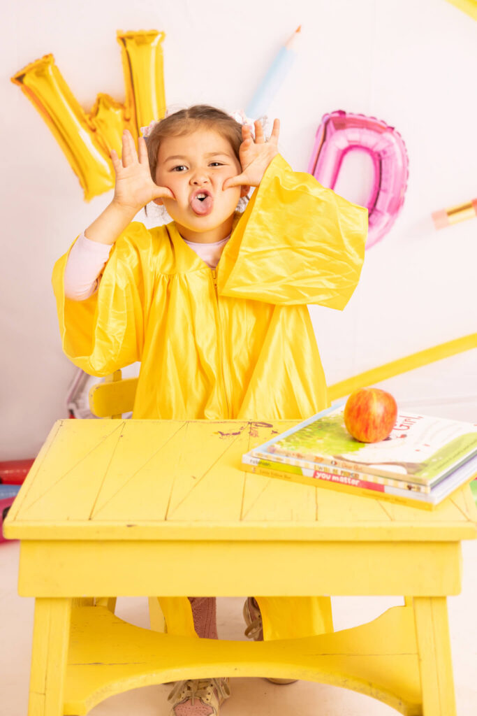 Preschool age girl pulling faces in a fun graduating photoshoot in LA