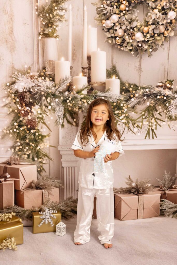 Little girl with a present standing in white pjamas at Christmas time in LA with LA photographer Elsie Rose Photography