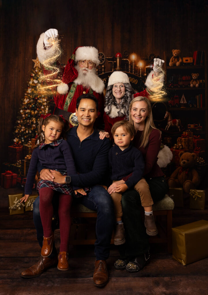 A family of 4 posing with Santa dn Mrs Claus for a photograph 